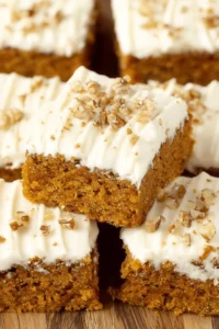 Delicious carrot cake bars with cream cheese frosting on a plate.