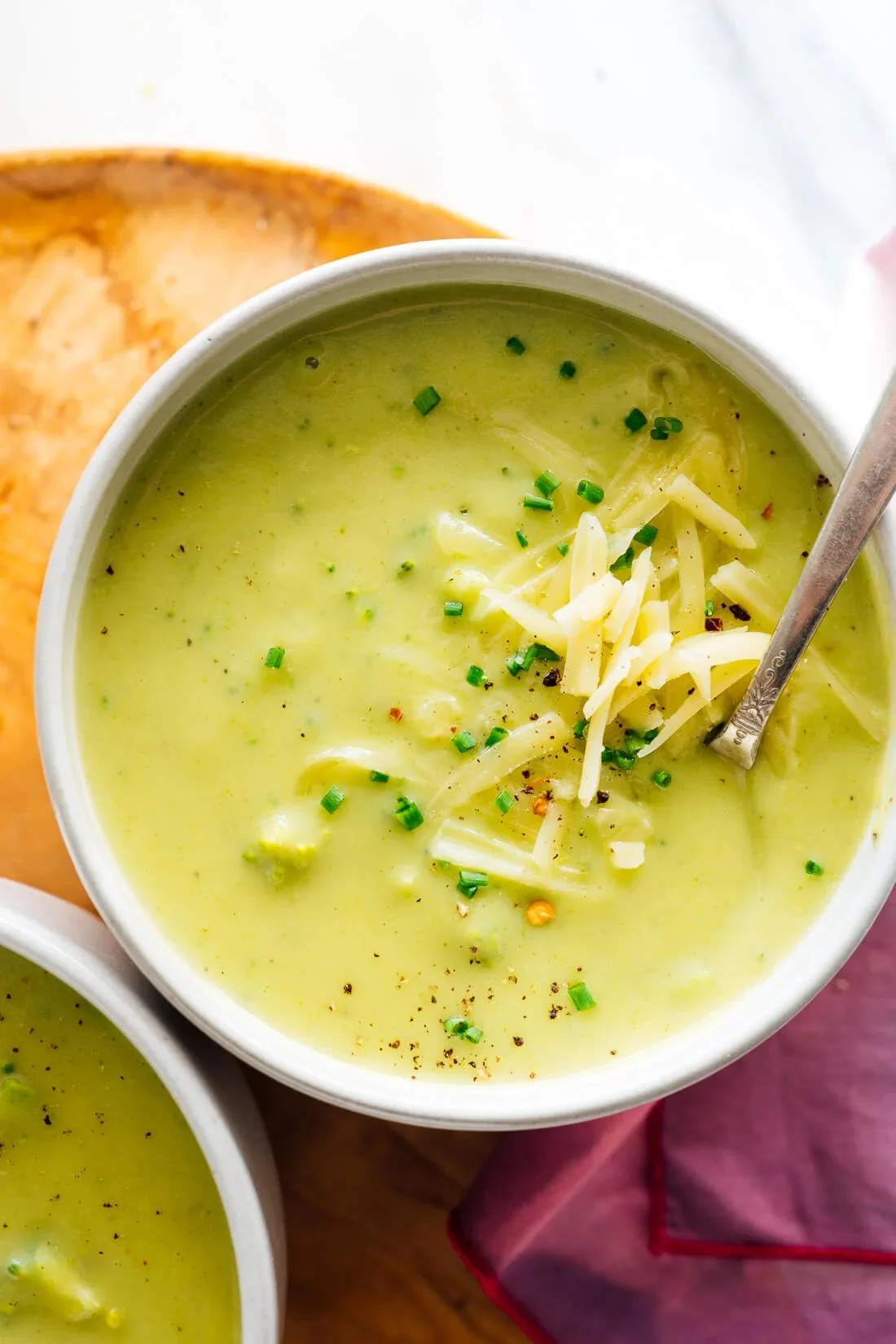 A bowl of creamy Broccoli Cheese Soup garnished with fresh broccoli and cheese