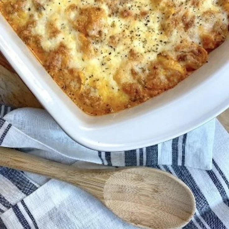 Cheesy baked tortellini casserole with meat sauce in a baking dish