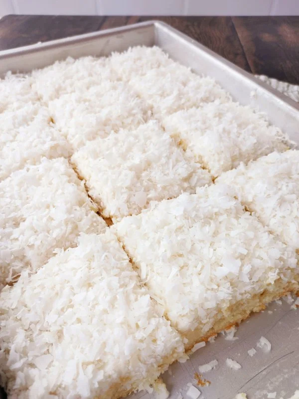 Delicious Coconut Texas Sheet Cake served on a platter with coconut flakes on top