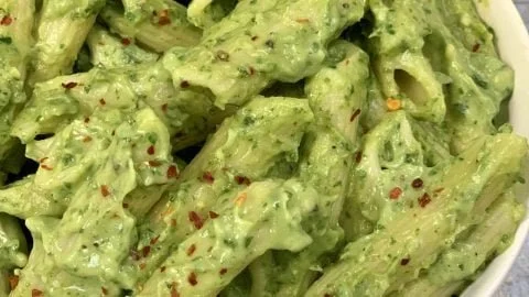 Creamy avocado pasta dish garnished with herbs