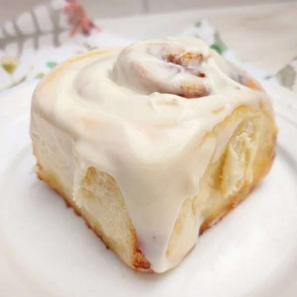 Delicious cinnamon rolls drizzled with cream cheese icing on a wooden table