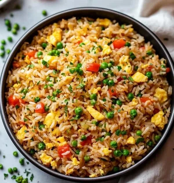 Plate of flavorful Egg Fried Rice garnished with vegetables and egg