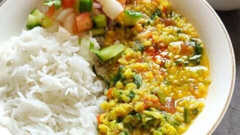 Bowl of delicious lentil spinach curry garnished with fresh herbs