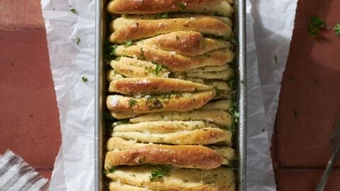 Fresh sourdough discard garlic pull apart bread on a wooden cutting board.