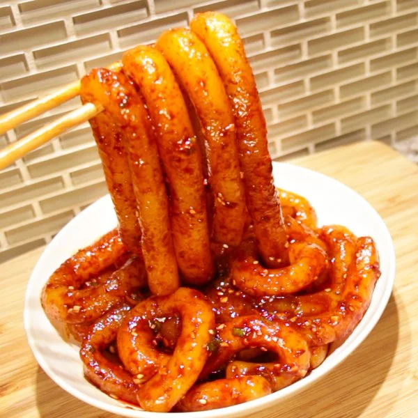 Bowl of spicy potato noodles garnished with herbs and spices