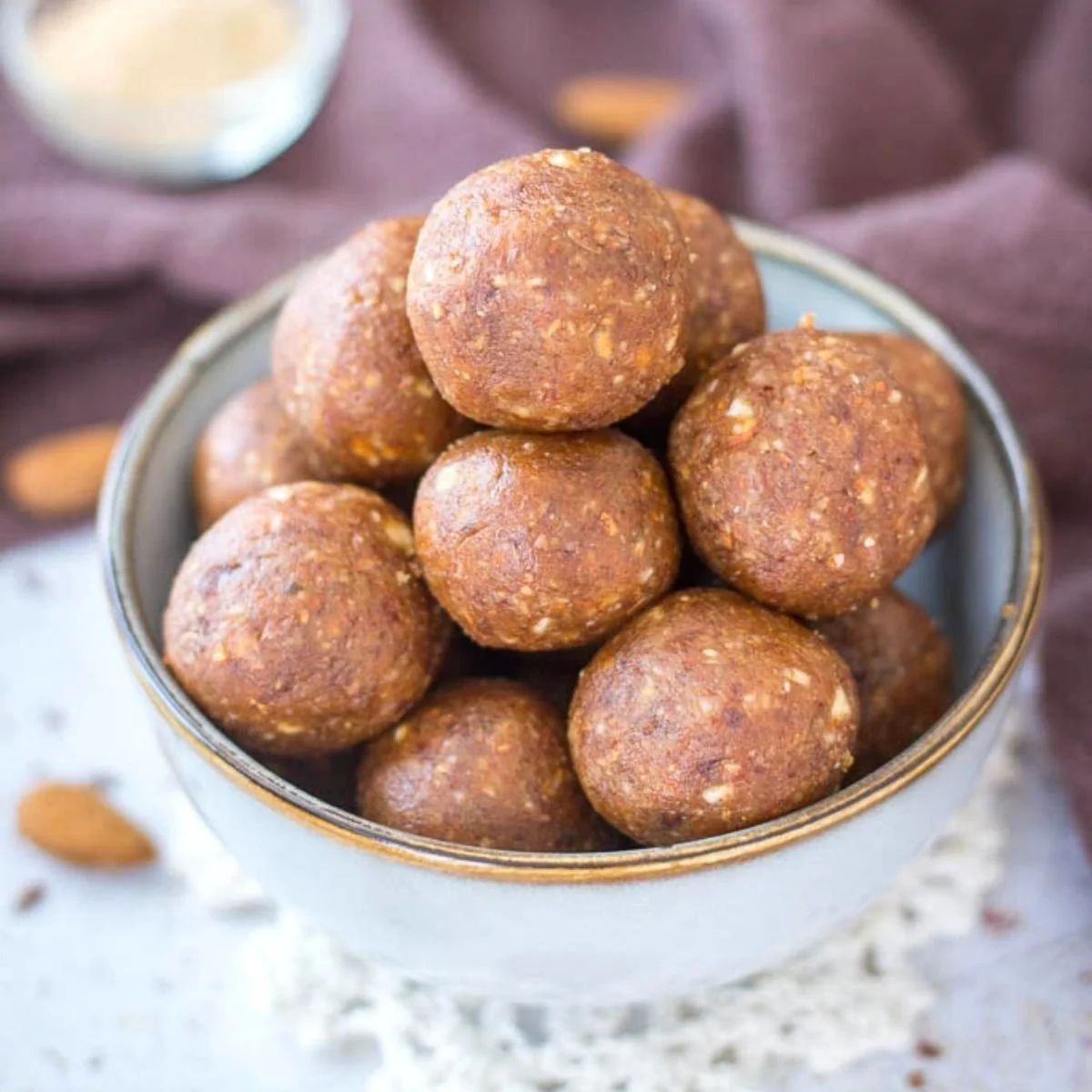 Homemade almond butter energy balls arranged on a wooden platter.