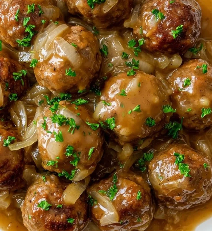 Plate of delicious smothered meatballs topped with savory sauce and herbs